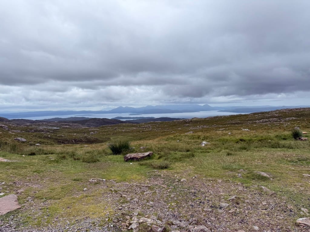 Highland moorland with distant islands beneath dark clouds.