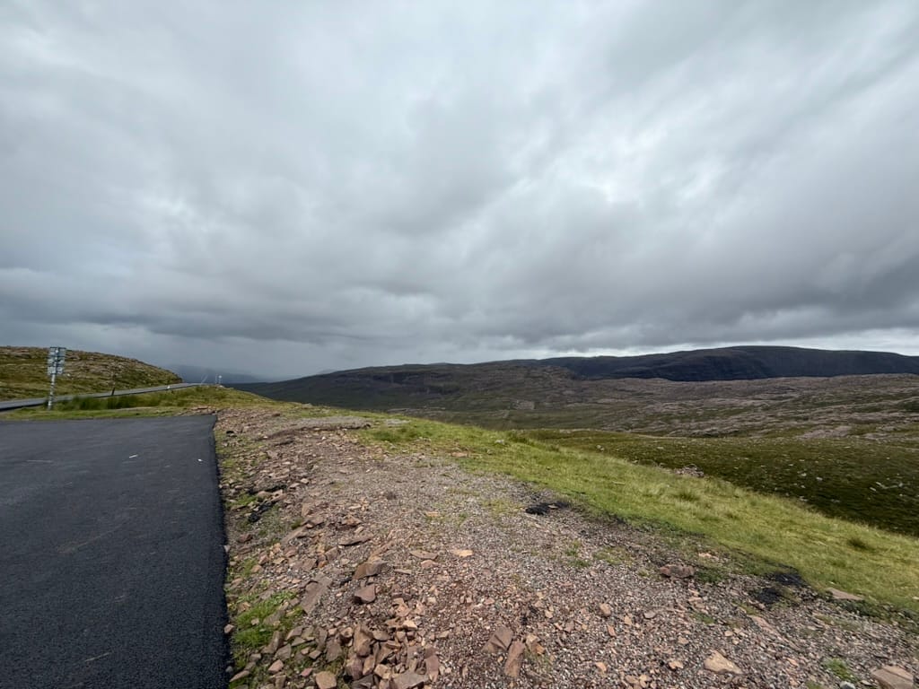Remote moorland road under stormy skies.