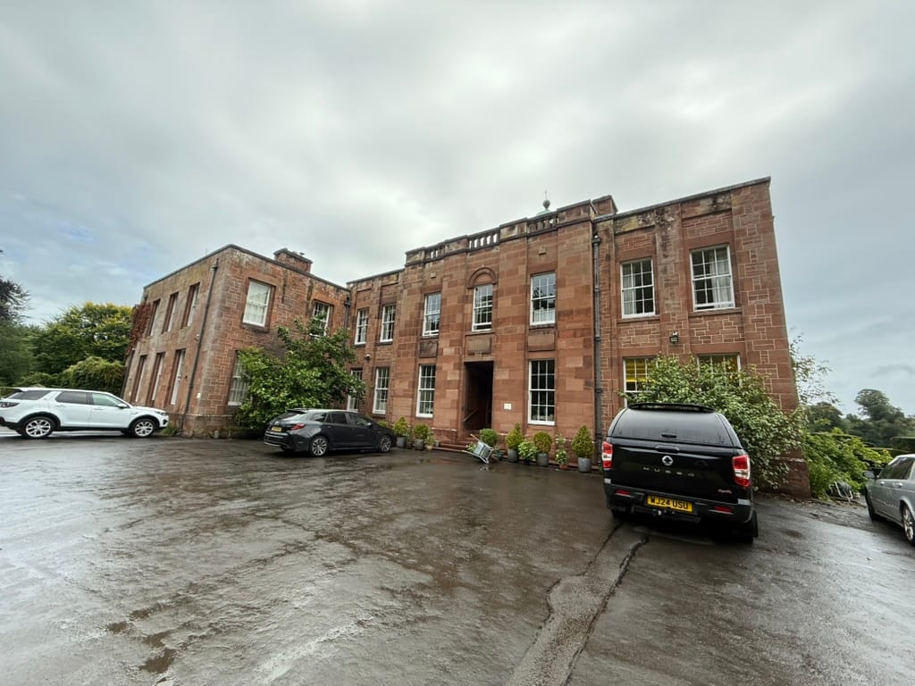 Historic sandstone hotel building on a rainy day.