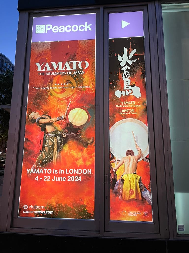 Advertisement for Yamato: The Drummers of Japan displayed outside the Peacock Theatre in London, featuring dramatic images of taiko drummers against a fiery red and orange background.