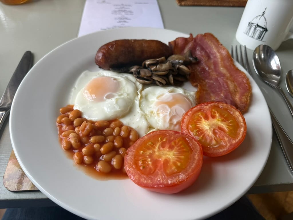 Cooked breakfast with eggs, bacon, sausage, beans, mushrooms and grilled tomatoes.