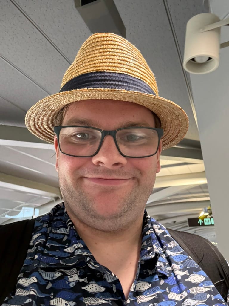 Traveller wearing a straw hat, glasses and a patterned shirt takes a selfie inside Kansai International Airport shortly after arriving in Japan.