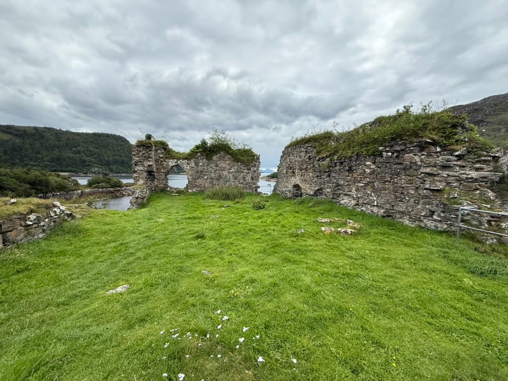 Lochside stone ruins under cloudy skies.