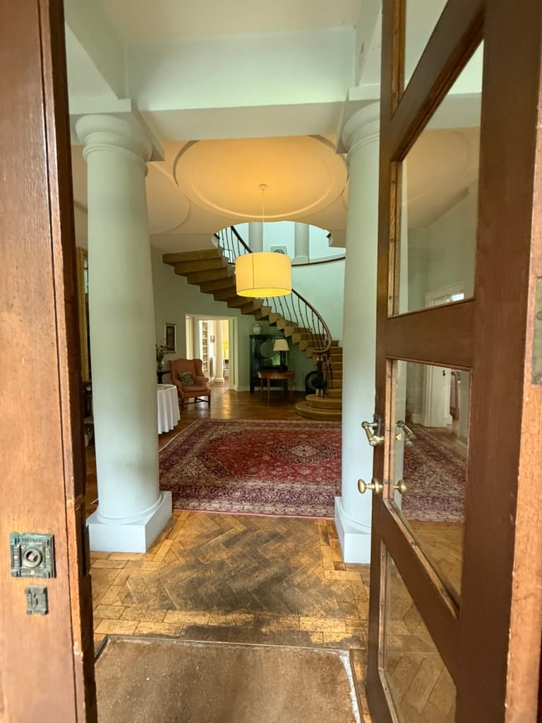Hotel entrance hall with columns and curved staircase.