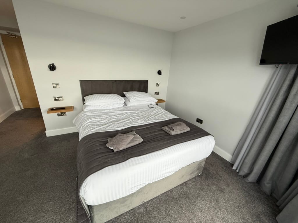 Modern hotel room with double bed and wall-mounted TV.