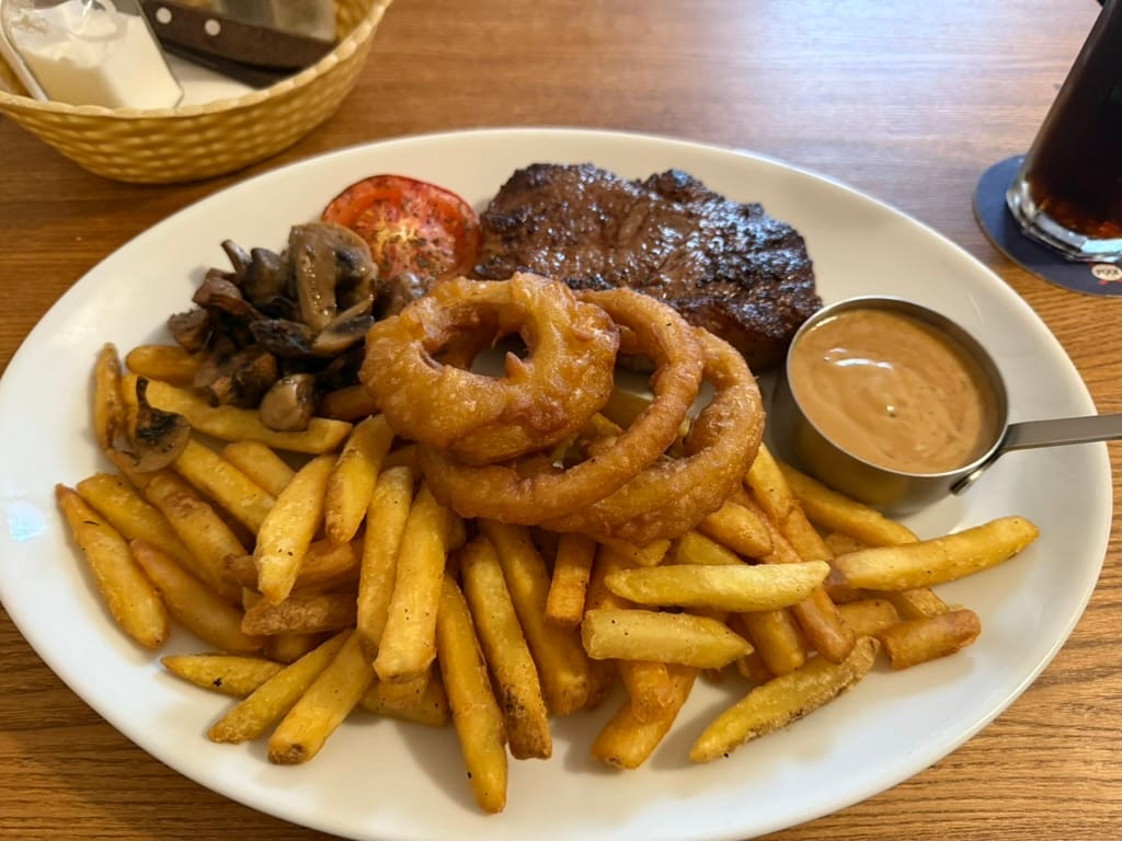 Steak with chips, onion rings and peppercorn sauce.