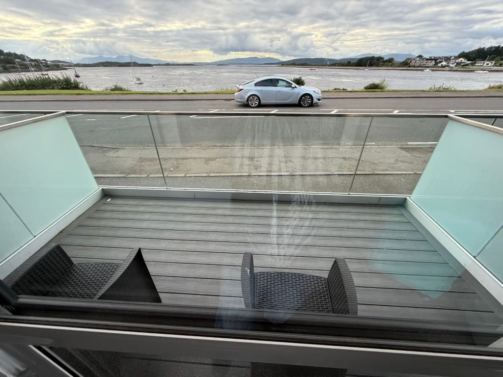 Balcony overlooking a sea loch and distant mountains.