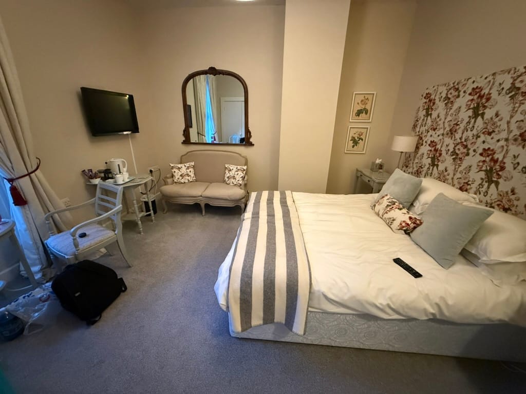 Traditional hotel room with floral decor and double bed.
