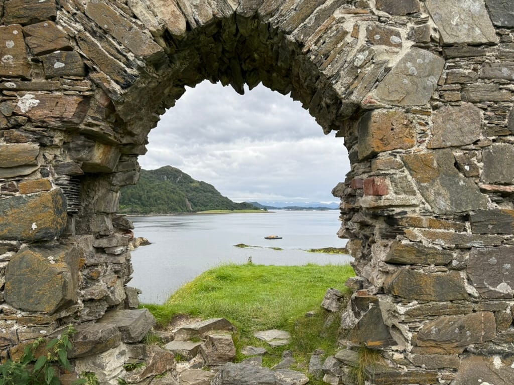 View through a castle archway over a Scottish loch.