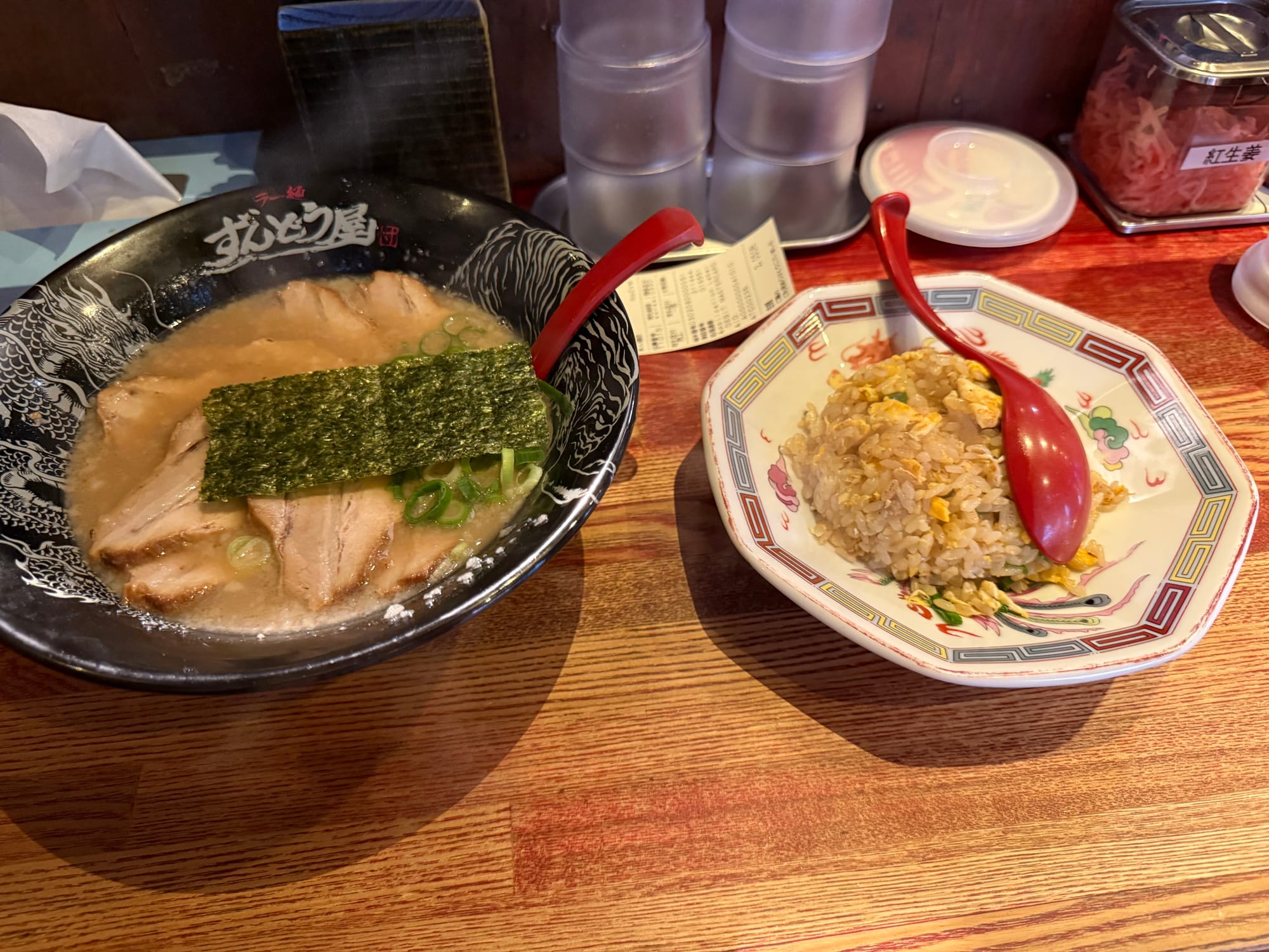 Bowl of tonkotsu ramen topped with sliced pork, spring onions and nori, served with a side of fried rice at a ramen restaurant in Osaka.