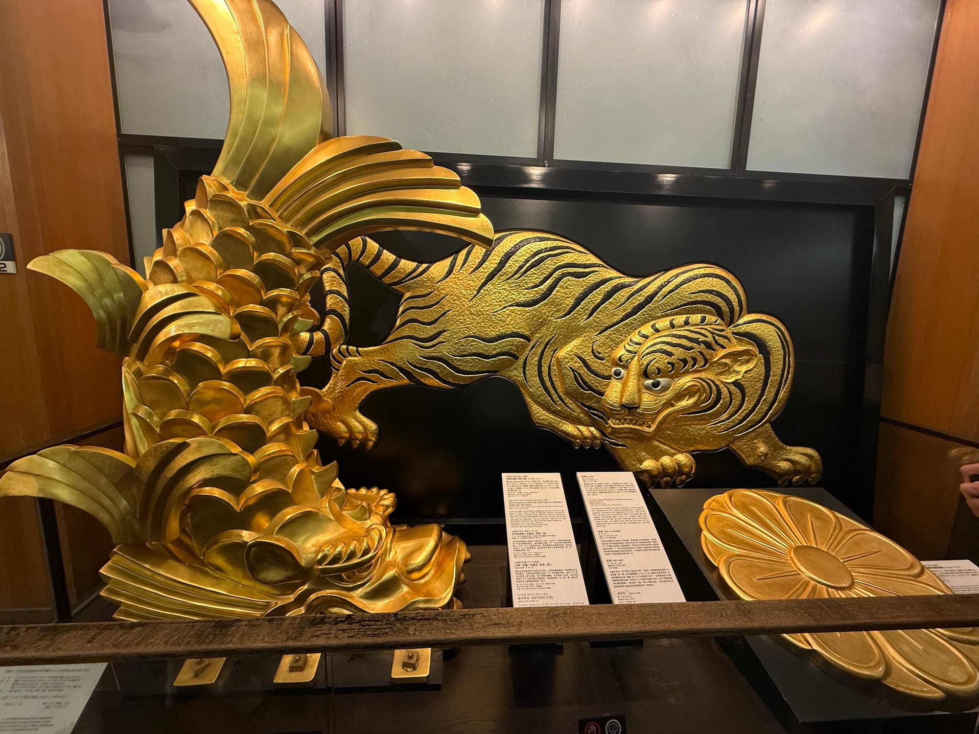 Golden shachihoko and tiger ornaments from Osaka Castle on display inside the castle museum, showcasing decorative symbols associated with the historic fortress.