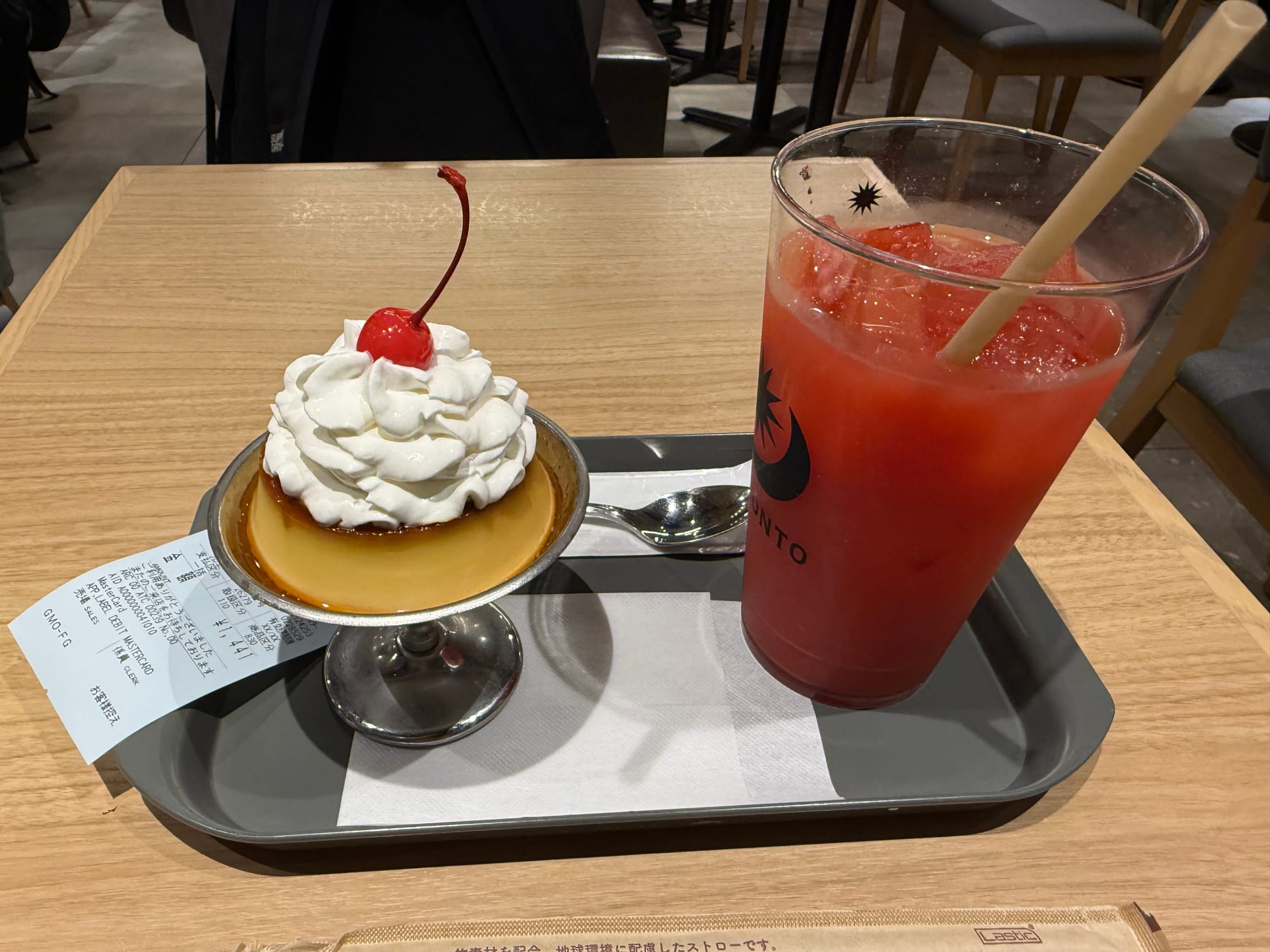 Caramel pudding topped with whipped cream and a cherry, served with a large iced watermelon drink on a tray in a café at Shin-Ōsaka Station.