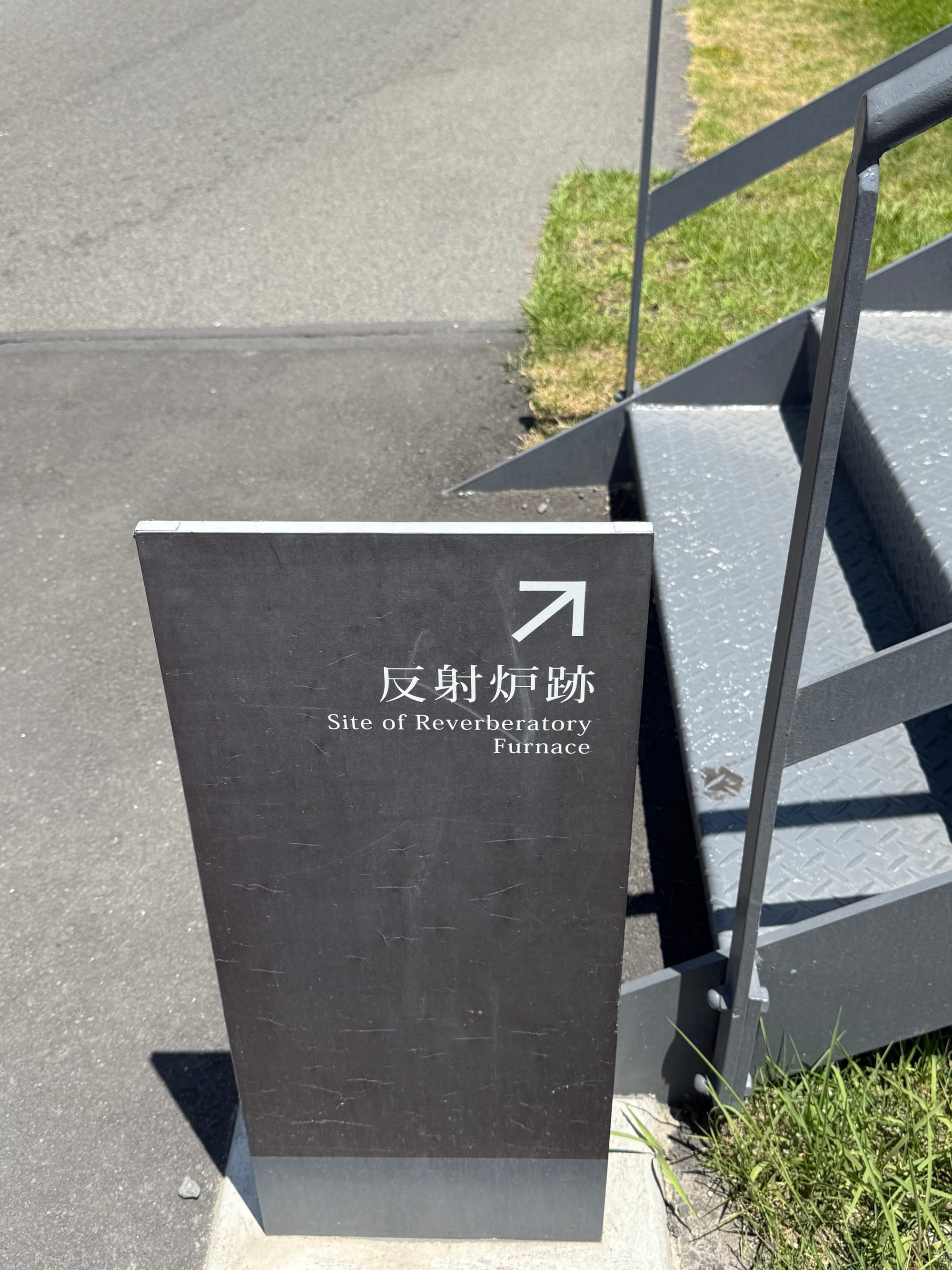 Sign at Sengan-en marking the site of a reverberatory furnace, with bilingual Japanese and English text directing visitors towards this historic industrial landmark.