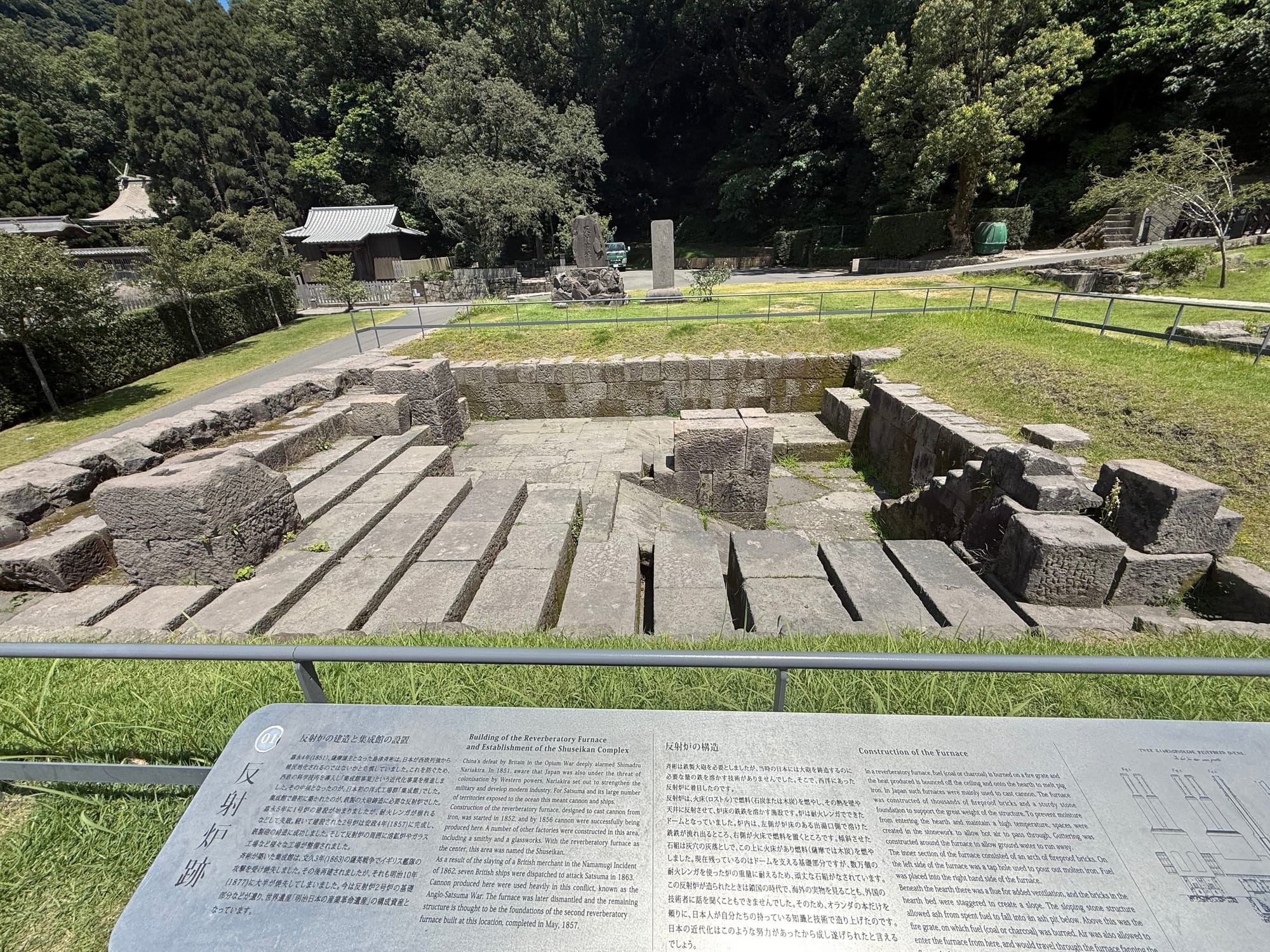 Copilot said:  Alt text (under 191 characters):  Remains of the reverberatory furnace at Sengan-en, with preserved stone foundations and an interpretation panel explaining the industrial site and its nineteenth-century construction.