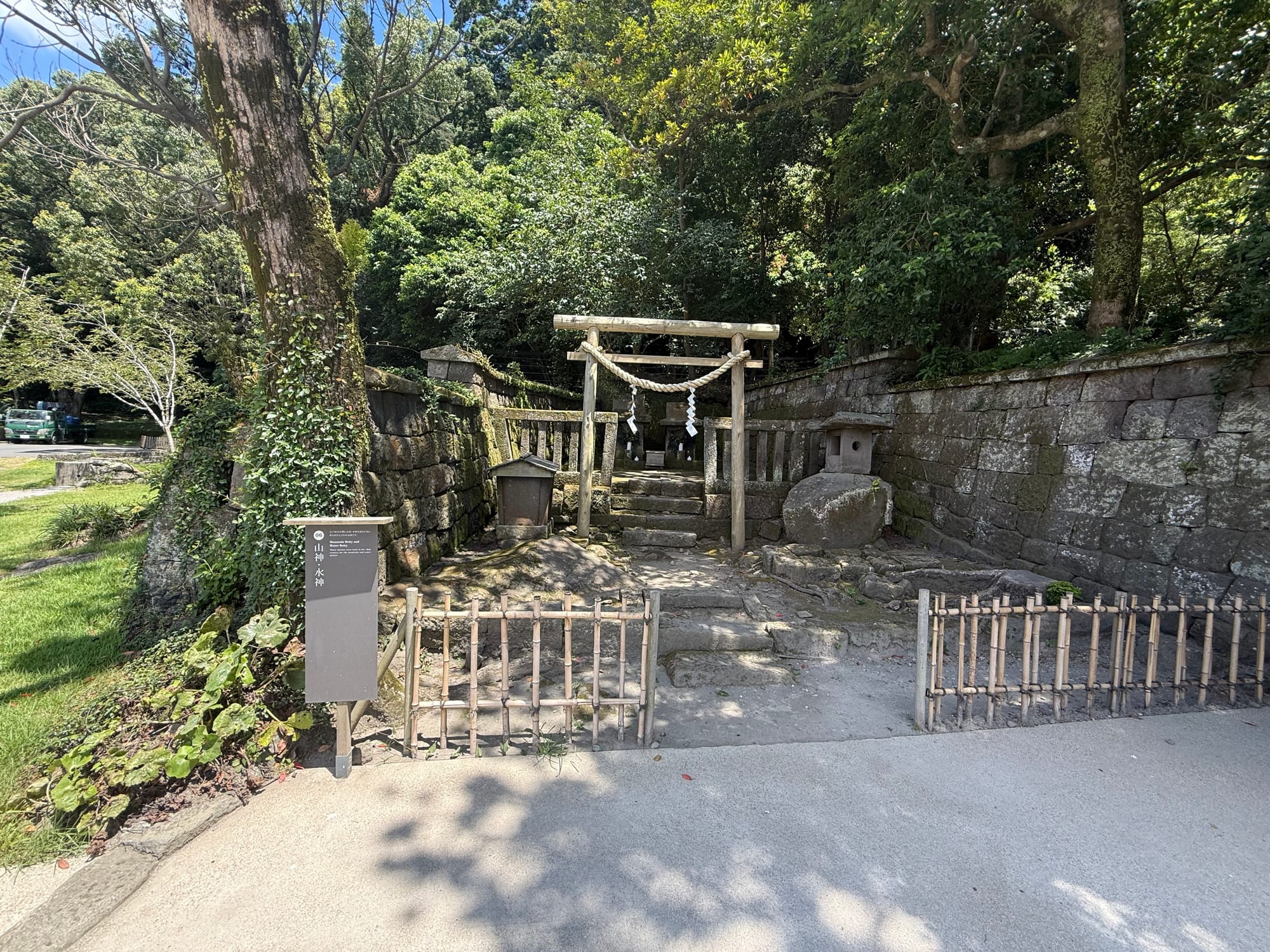 Small shrine dedicated to mountain and water deities at Sengan-en, featuring a wooden torii gate, stone lanterns and a shaded setting beneath mature trees.
