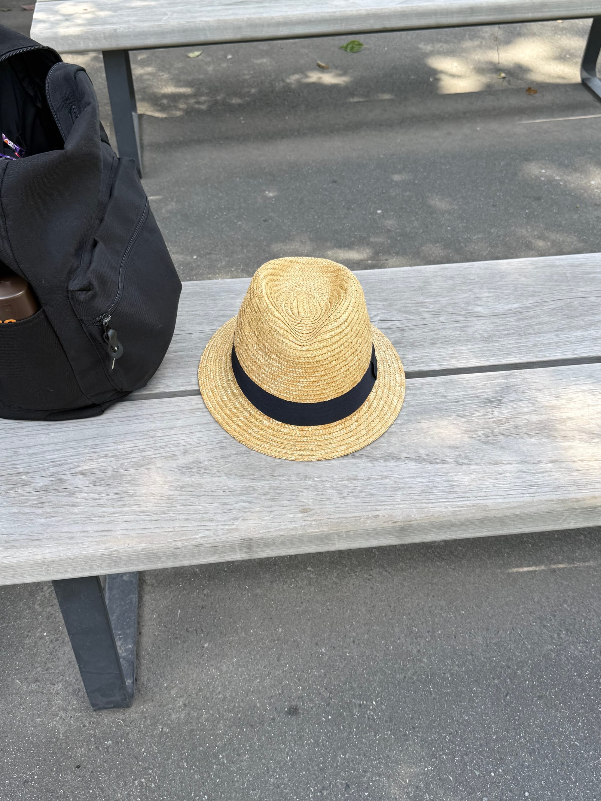 Straw hat with a black band, affectionately known as "Mr Hat", resting on a wooden bench beside a backpack during a break at Sengan-en in Kagoshima.