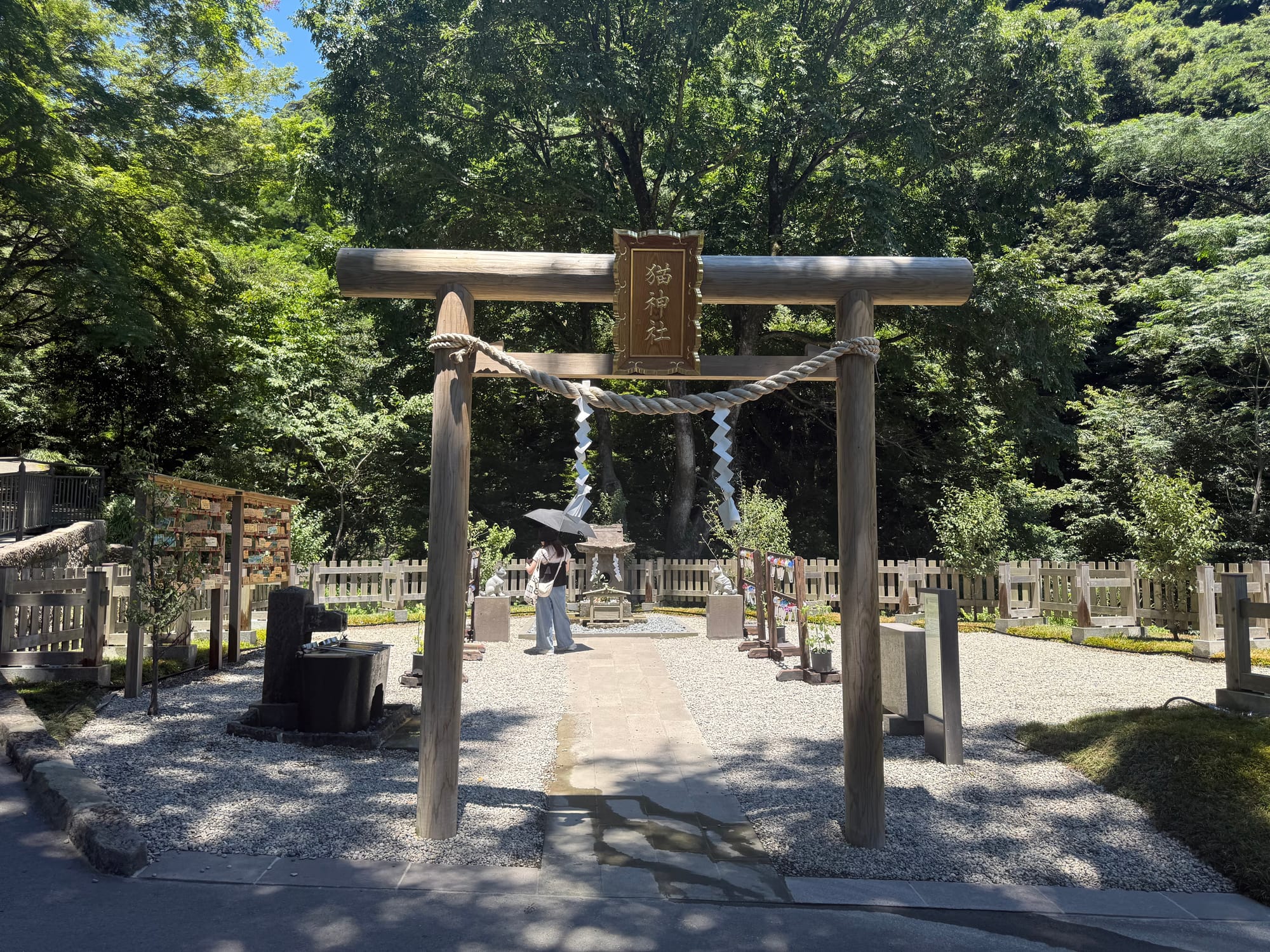 Cat Shrine at Sengan-en in Kagoshima, featuring a wooden torii gate, gravel pathway, shrine building and commemorative displays set among trees and woodland.