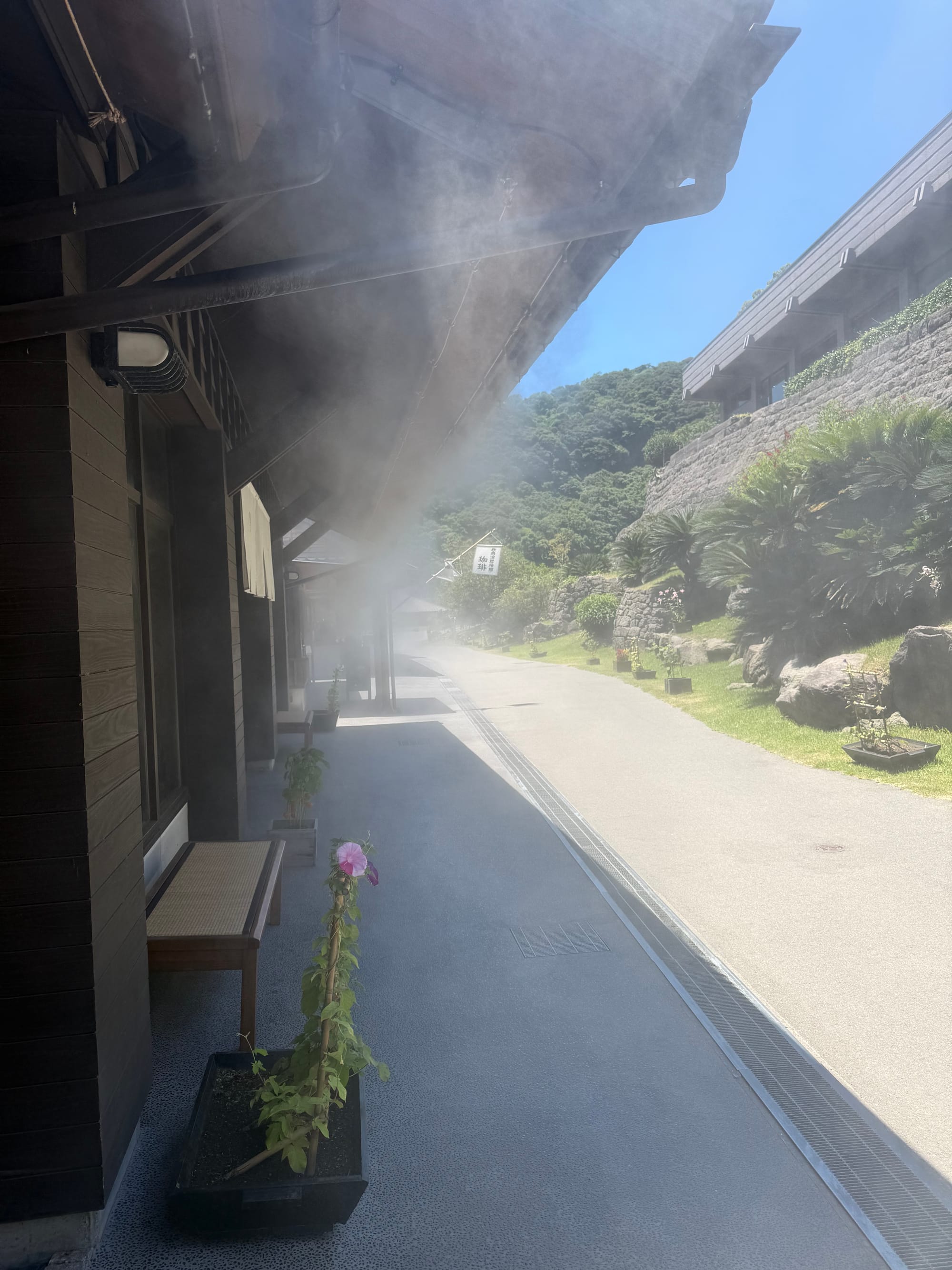 Cooling mist drifts from overhead sprayers along a walkway at Sengan-en, providing relief from the summer heat beside traditional buildings and landscaped grounds.