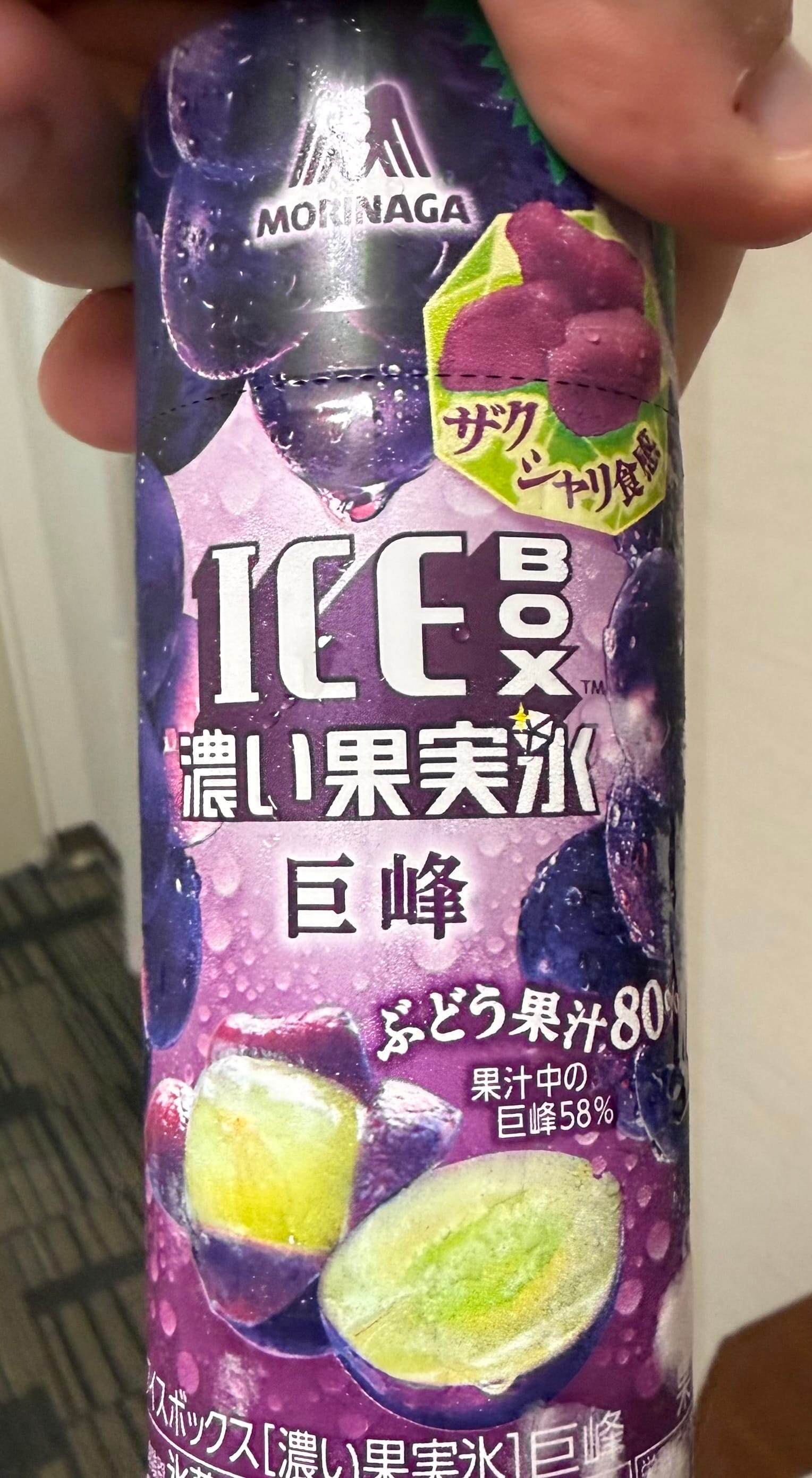 Morinaga ICE BOX giant grape-flavoured ice drink, showing purple grape imagery and Japanese text on the packaging, held indoors in Kagoshima.