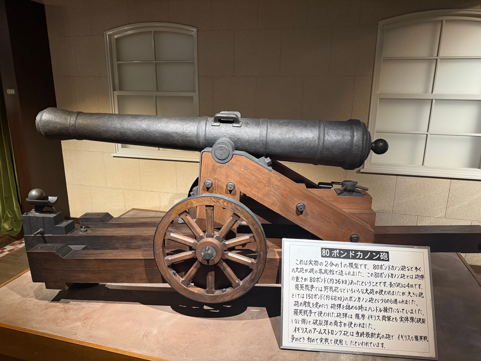 Model of an 80-pound cannon on display at the Museum of the Meiji Restoration in Kagoshima, mounted on a wooden carriage with an explanatory information panel.