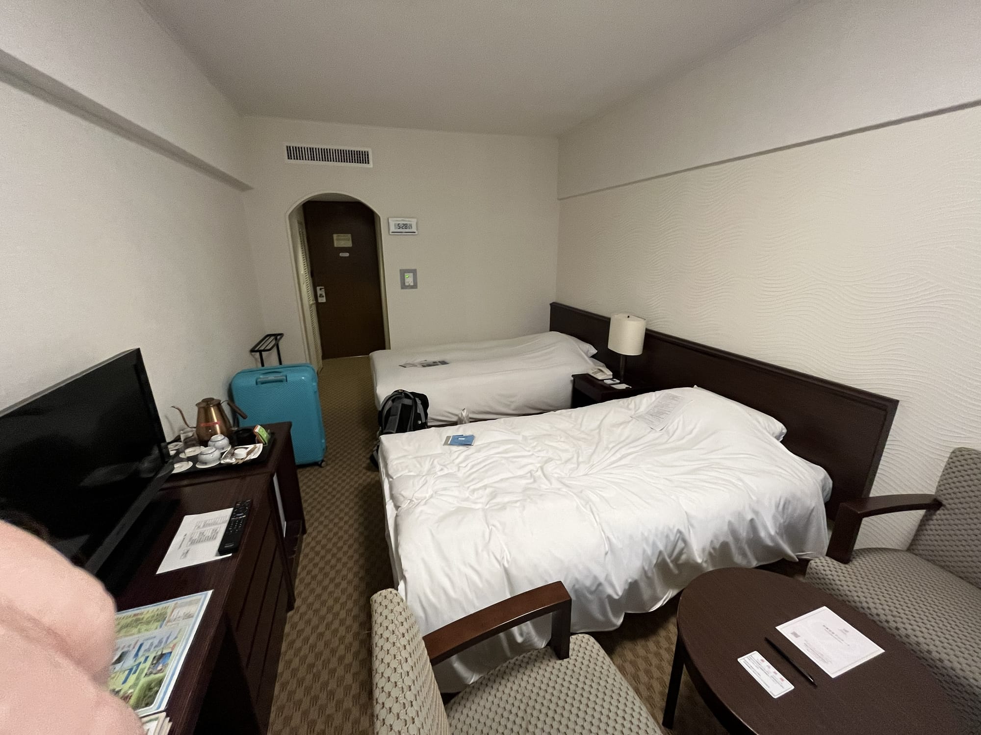 Twin room at Towada Prince Hotel, featuring two beds, a television, seating area, luggage and tea-making facilities overlooking Lake Towada.