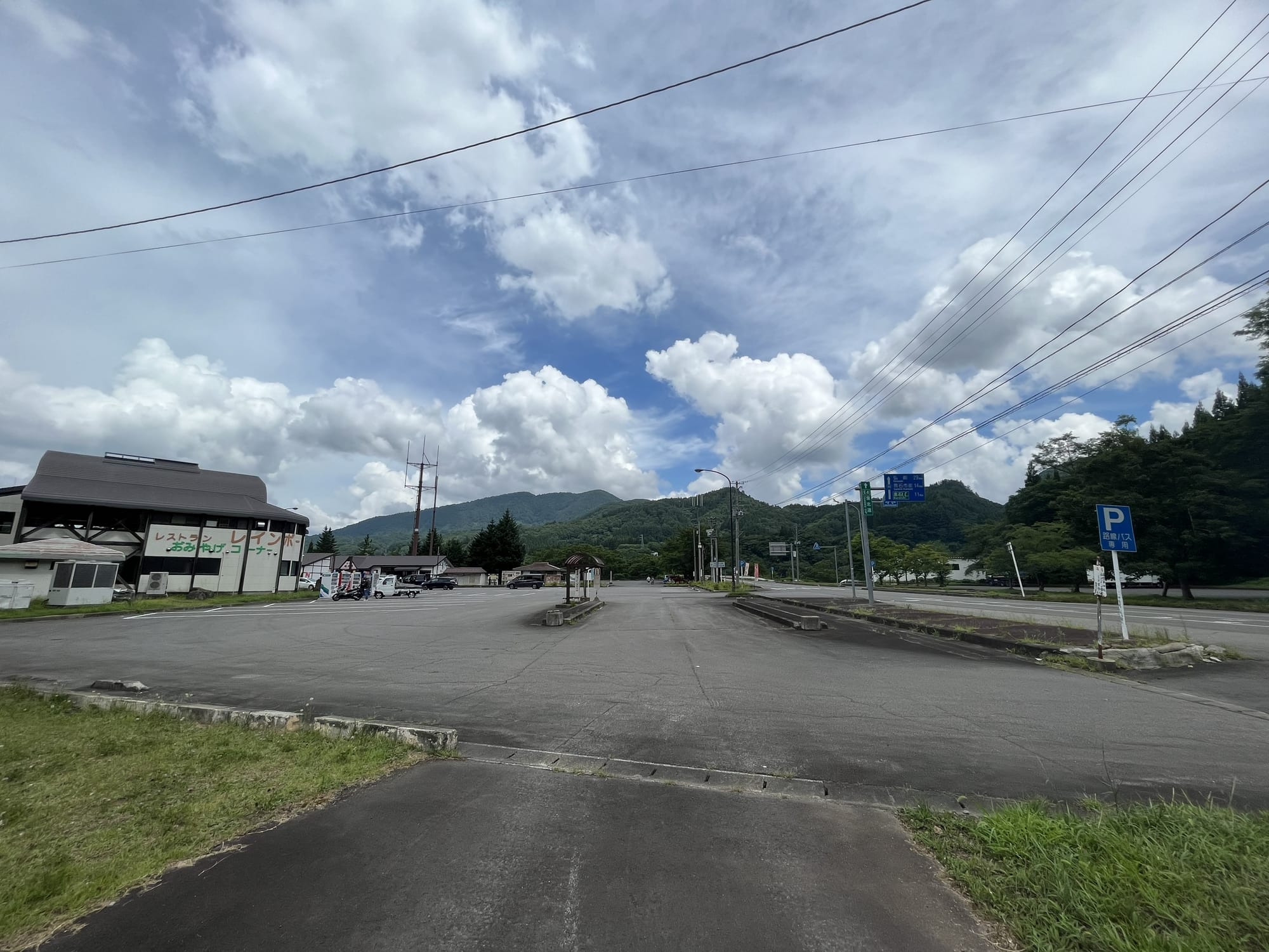 Roadside stop at Lake Oirase in northern Japan, with forested hills, quiet roads and dramatic summer clouds breaking to reveal patches of blue sky..