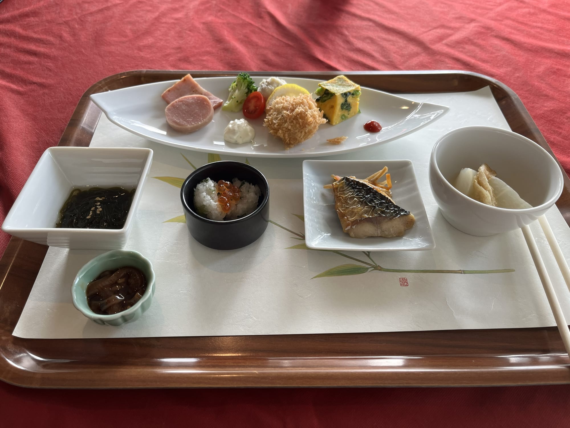 Japanese appetiser course at Towada Prince Hotel, featuring grilled fish, roe, seaweed, vegetables and assorted side dishes arranged on a tray with elegant tableware.