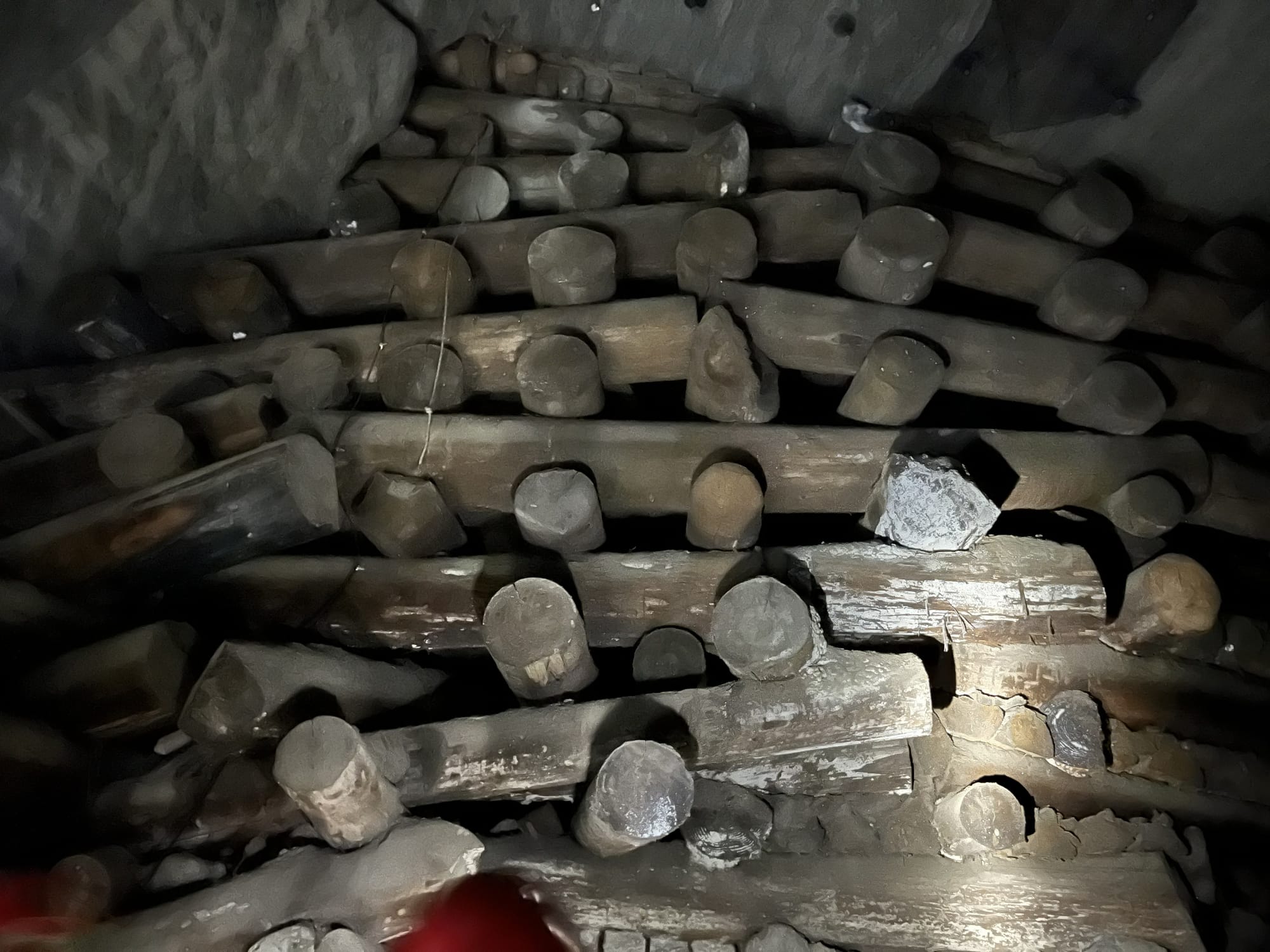 Stacked timber supports coated with salt deposits inside the Wieliczka Salt Mine, illuminated by dim underground lighting.
