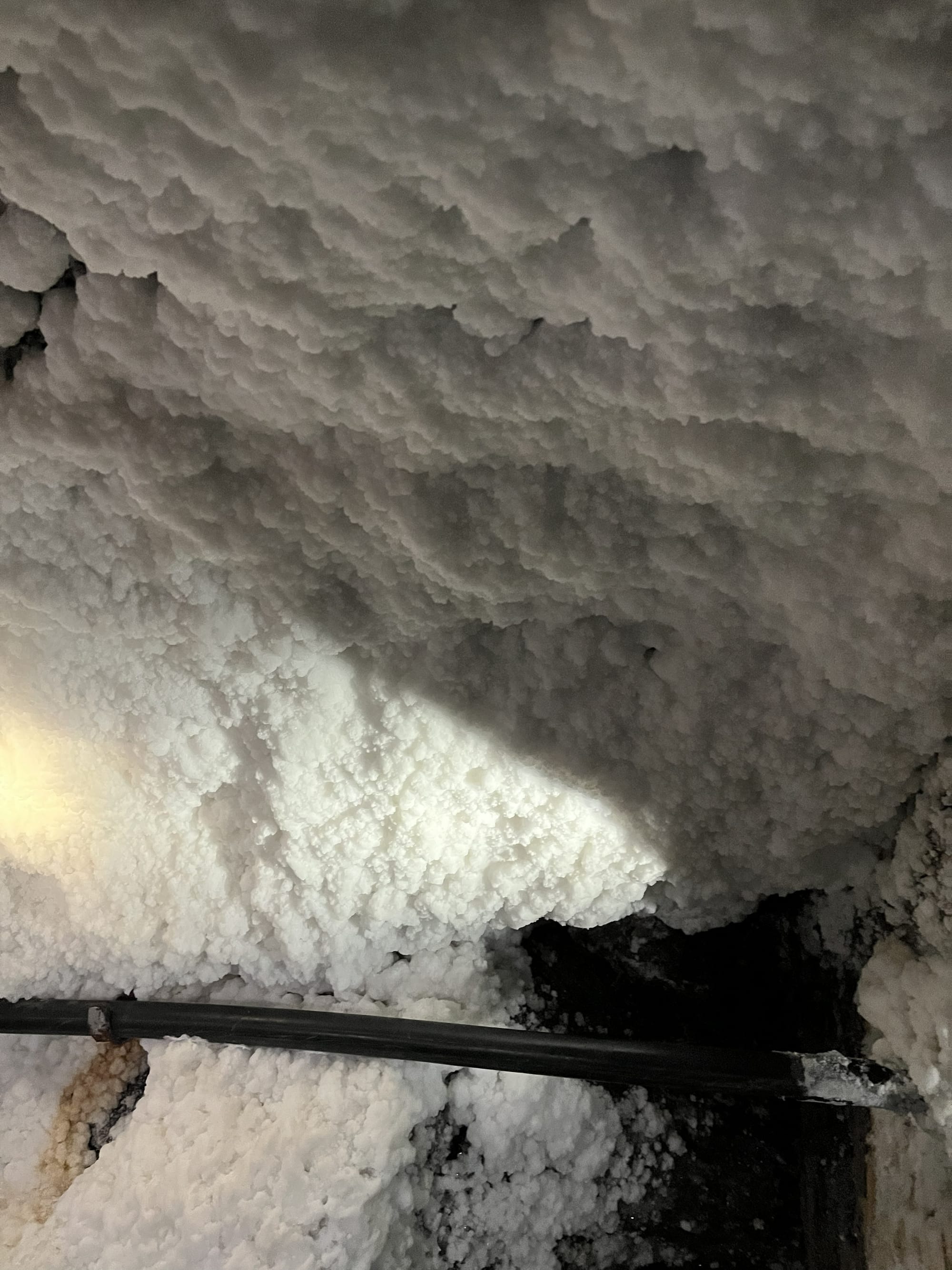 Thick white salt crystals covering the walls and ceiling of a chamber inside the Wieliczka Salt Mine, illuminated by artificial lighting.