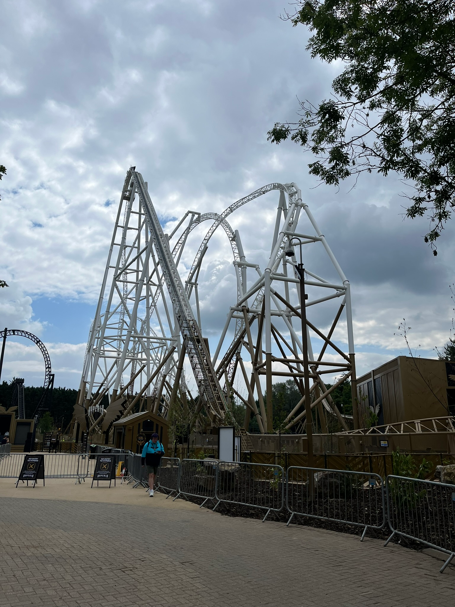 Hyperia roller coaster at Thorpe Park, featuring a towering white steel structure with steep drops, inversions and sweeping track elements beneath a dramatic cloudy sky.