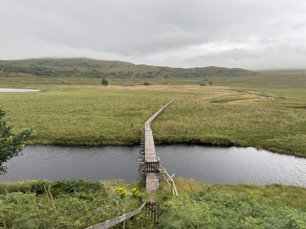 Wooden footbridge crossing a stream beside the A890 in the Scottish Highlands.