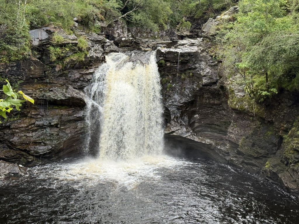 Falls of Falloch waterfall plunging into a deep rocky pool.