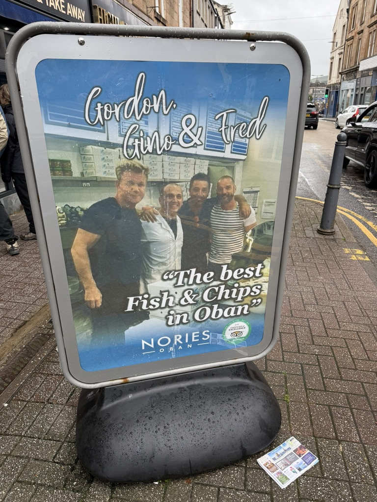 Sign outside Nories fish and chip shop in Oban featuring Gordon Ramsay, Gino D'Acampo and Fred Sirieix.