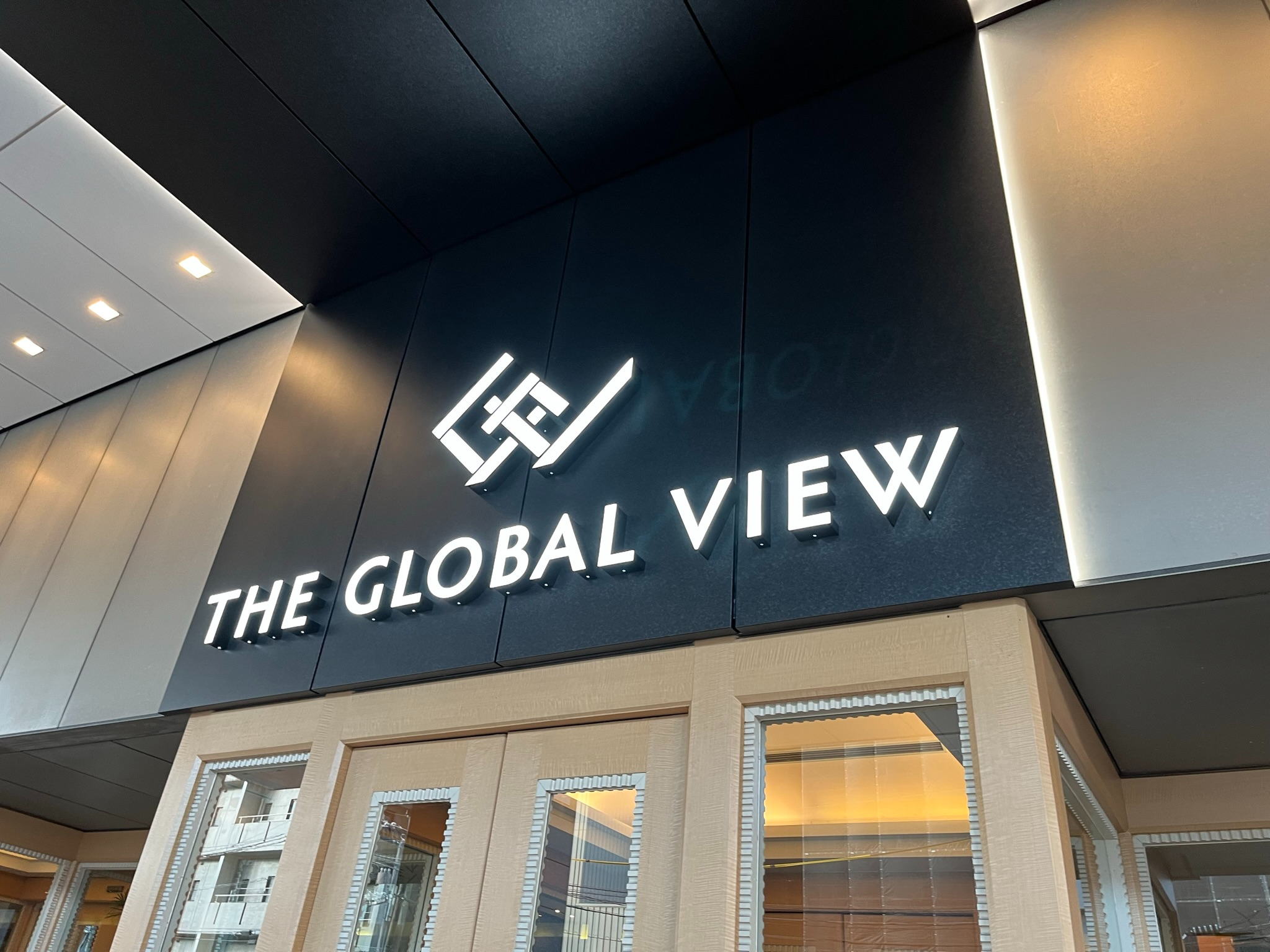 Illuminated sign for The Global View Nagasaki above the hotel entrance, featuring modern branding on a dark exterior wall with glass doors and contemporary architectural details.