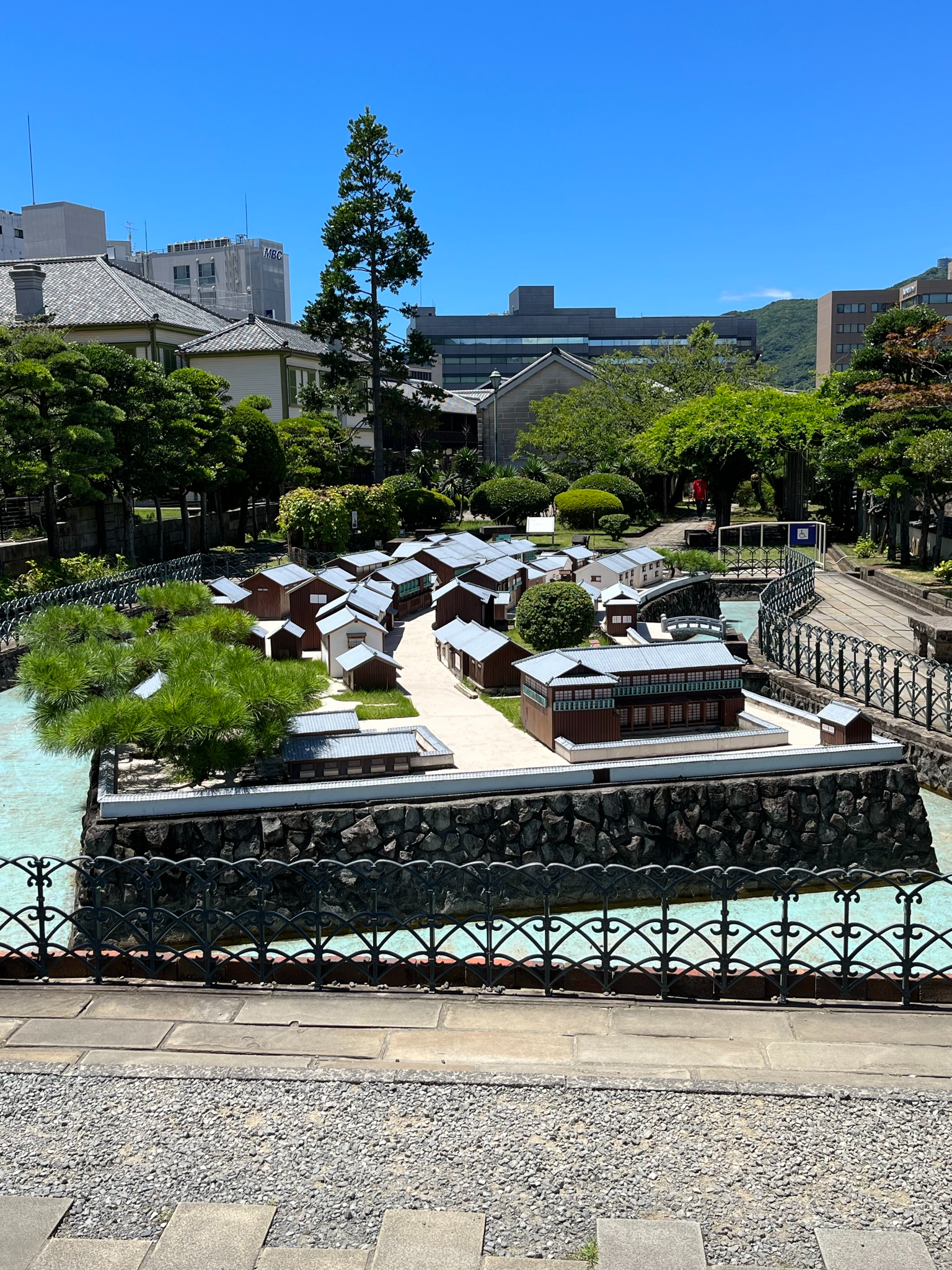 Scale model of historic Dejima in Nagasaki, showing reconstructed warehouses, residences, streets and waterways within the former Dutch trading post under clear blue skies.
