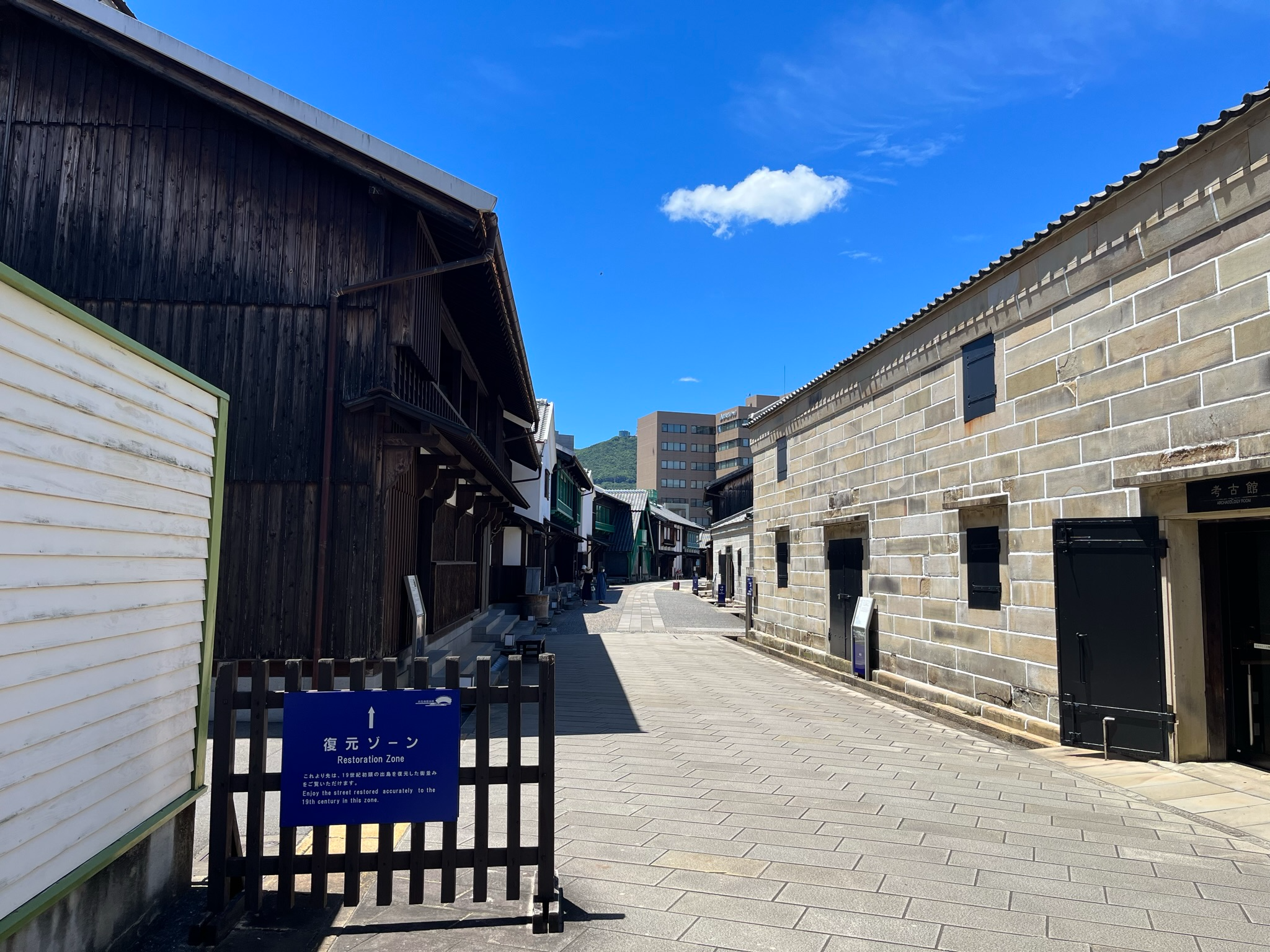 Street within Dejima's Restoration Zone in Nagasaki, lined with reconstructed wooden and stone buildings that recreate the appearance of the historic Dutch trading post.