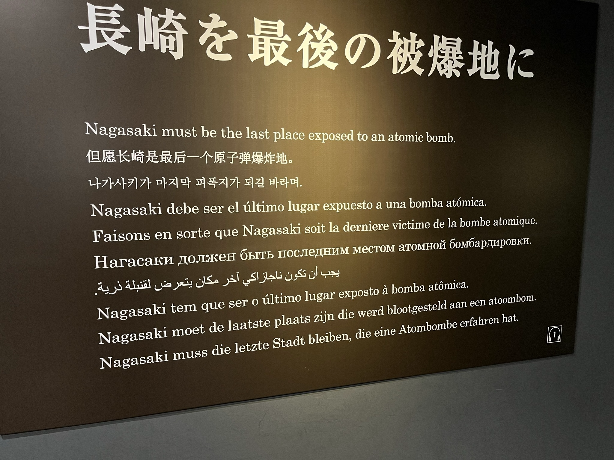 Museum display featuring the message "Nagasaki must be the last place exposed to an atomic bomb" presented in multiple languages at the Nagasaki Atomic Bomb Museum.