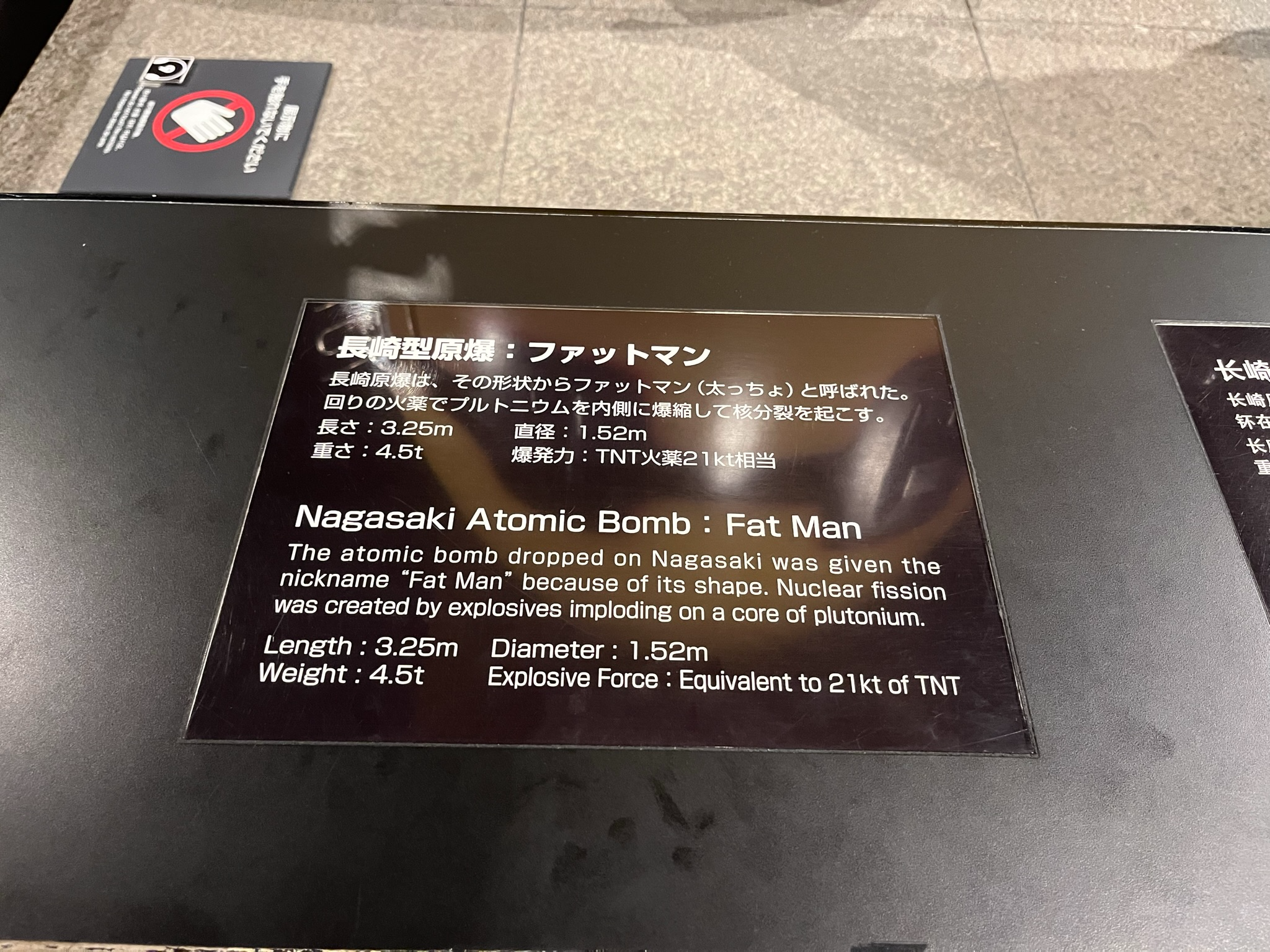 Information panel at the Nagasaki Atomic Bomb Museum describing the "Fat Man" atomic bomb, including its dimensions, weight and explosive force in Japanese and English.