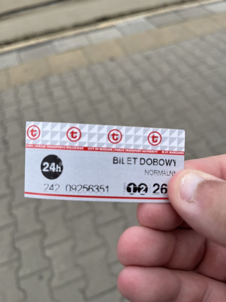 Warsaw public transport 24-hour ticket held on a station platform.