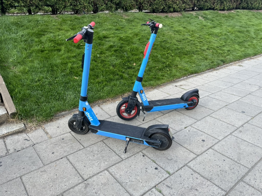Two blue rental e-scooters parked on a pavement in Warsaw.