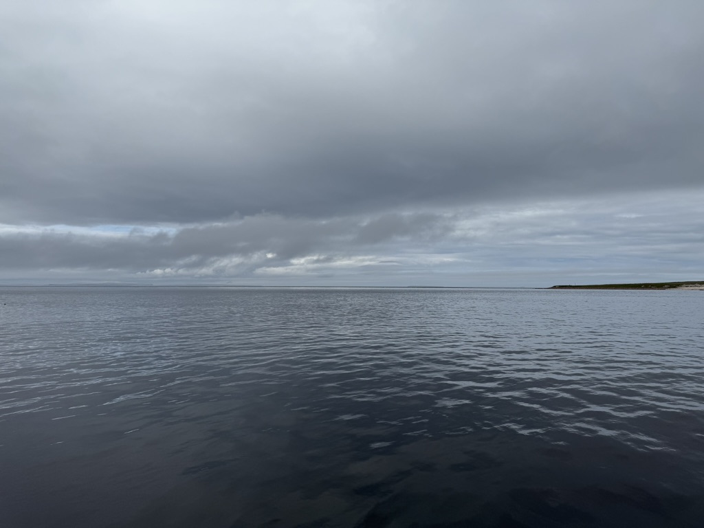 Calm sea at John O' Groats beneath dark storm clouds.