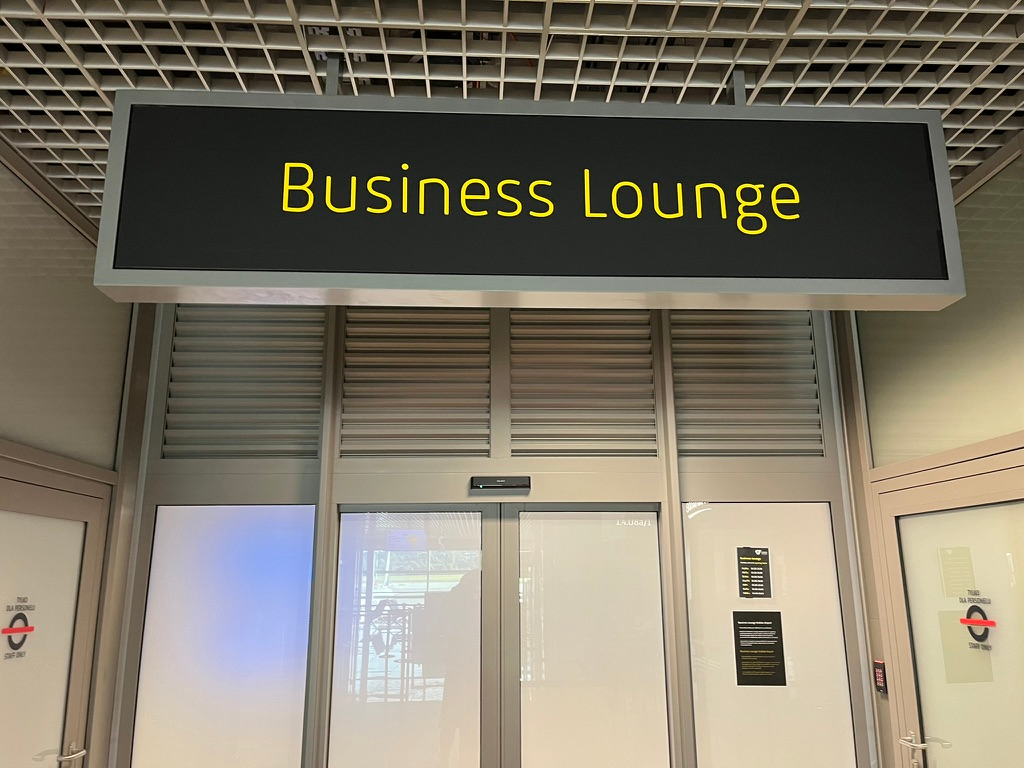 Entrance to the Business Lounge at Kraków Airport, marked by a large illuminated sign above sliding glass doors.
