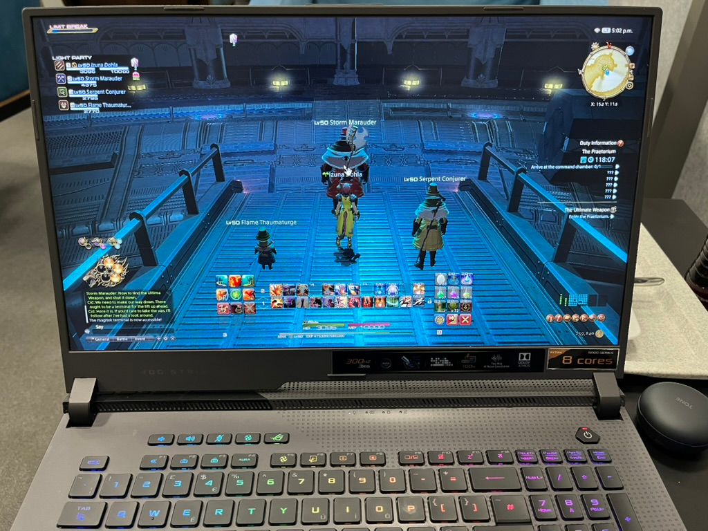 Gaming laptop displaying Final Fantasy XIV, with a party of characters gathered in a futuristic dungeon environment.