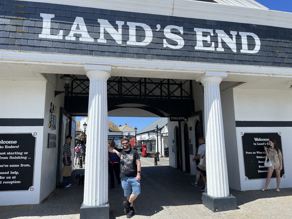 Person standing beneath the Land's End entrance arch in Cornwall.