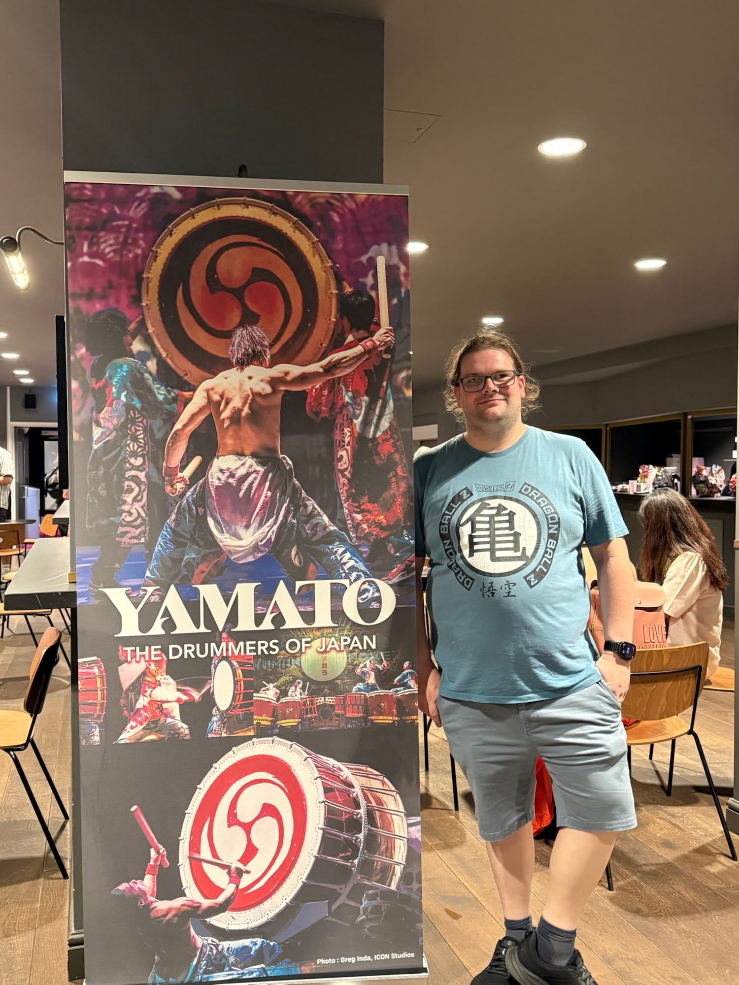 Visitor standing beside a Yamato Drummers of Japan promotional banner at the Peacock Theatre.