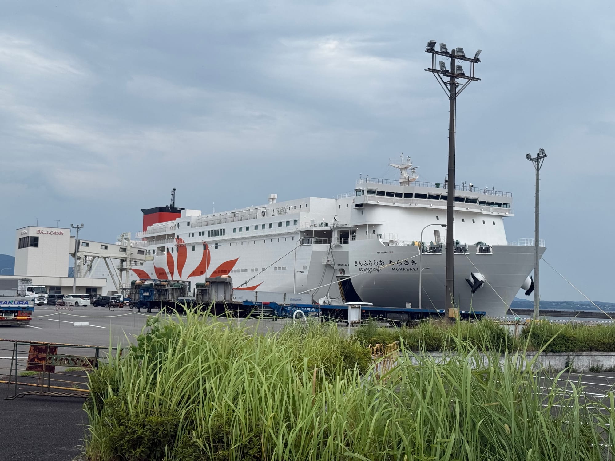 Sunflower Ferry Sunflower Murasaki berthed at Beppu Port, with its distinctive orange sunflower livery visible on the hull beneath an overcast summer sky.