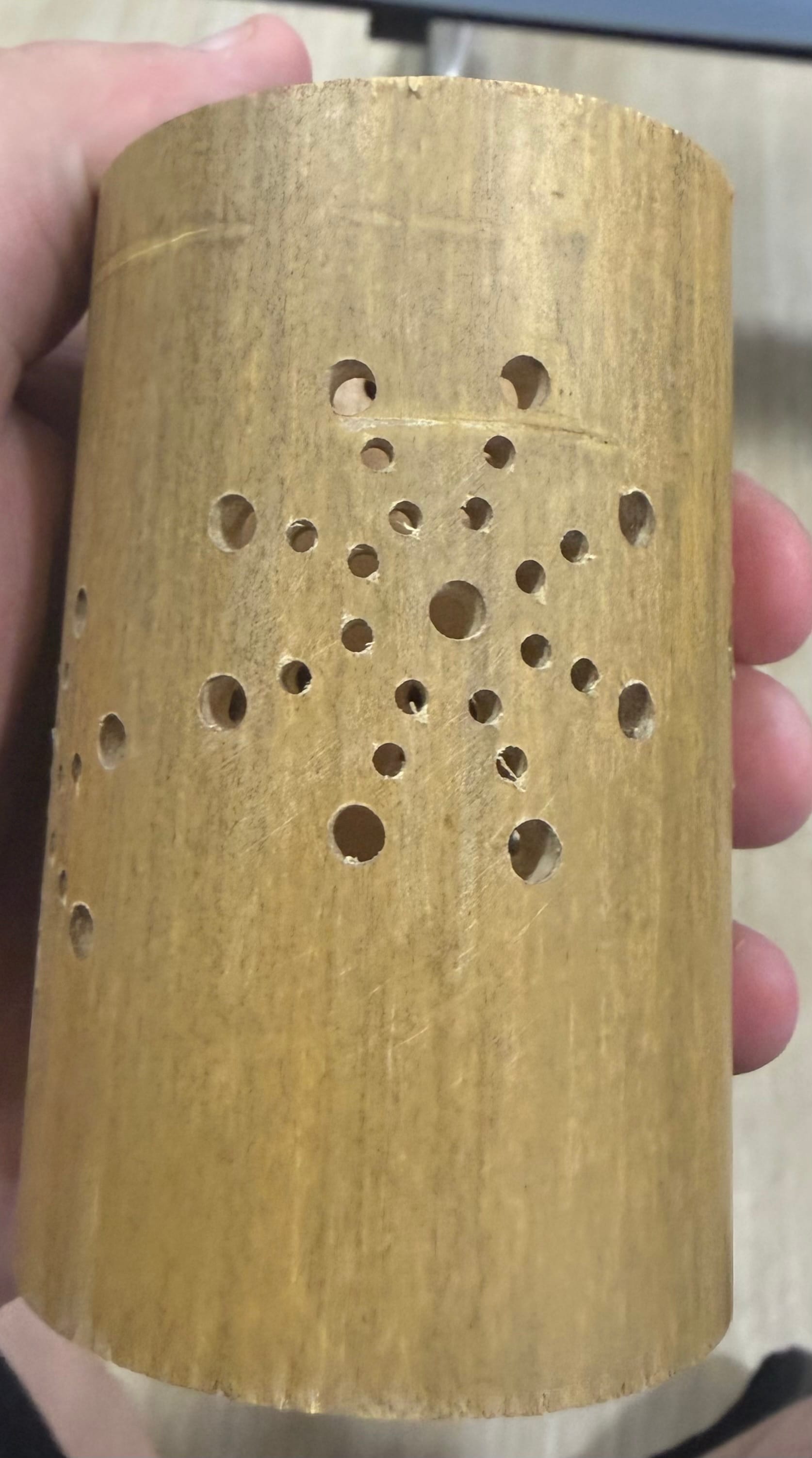 Hand holding a bamboo craft with a pattern of drilled holes, created during a workshop at Space Beppu, showing traditional craftsmanship and natural materials.