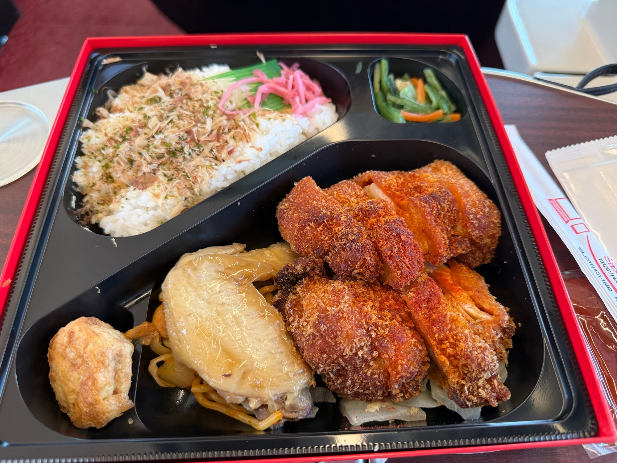 Hinotori-themed ekiben opened aboard the Kintetsu Hinotori limited express, featuring rice, crumbed pork cutlet, vegetables and side dishes served in a compartmented tray.
