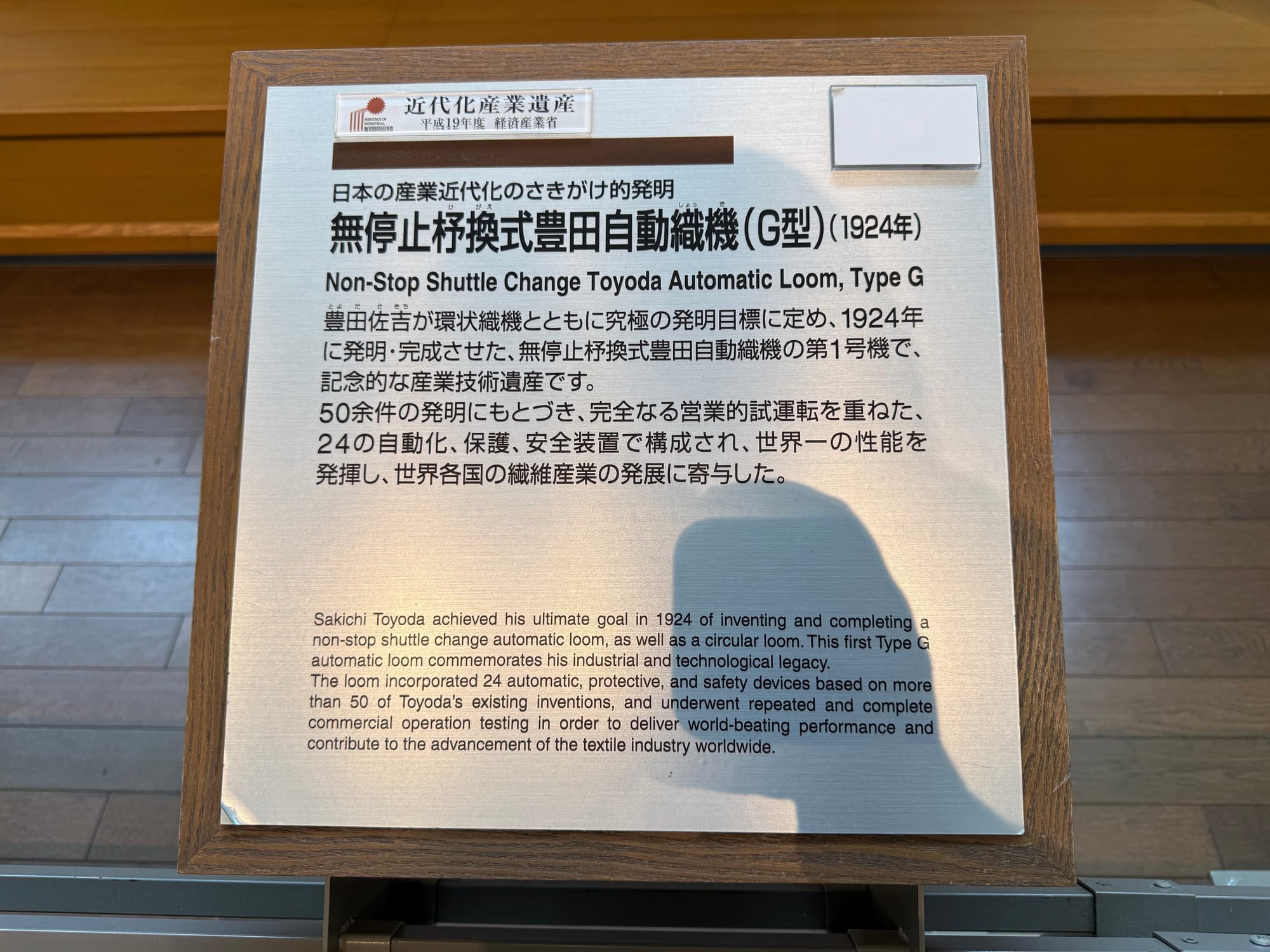 Exhibit panel at the Toyota Commemorative Museum of Industry and Technology explaining the Type G Toyoda Automatic Loom, developed in 1924 with automatic shuttle-changing technology.