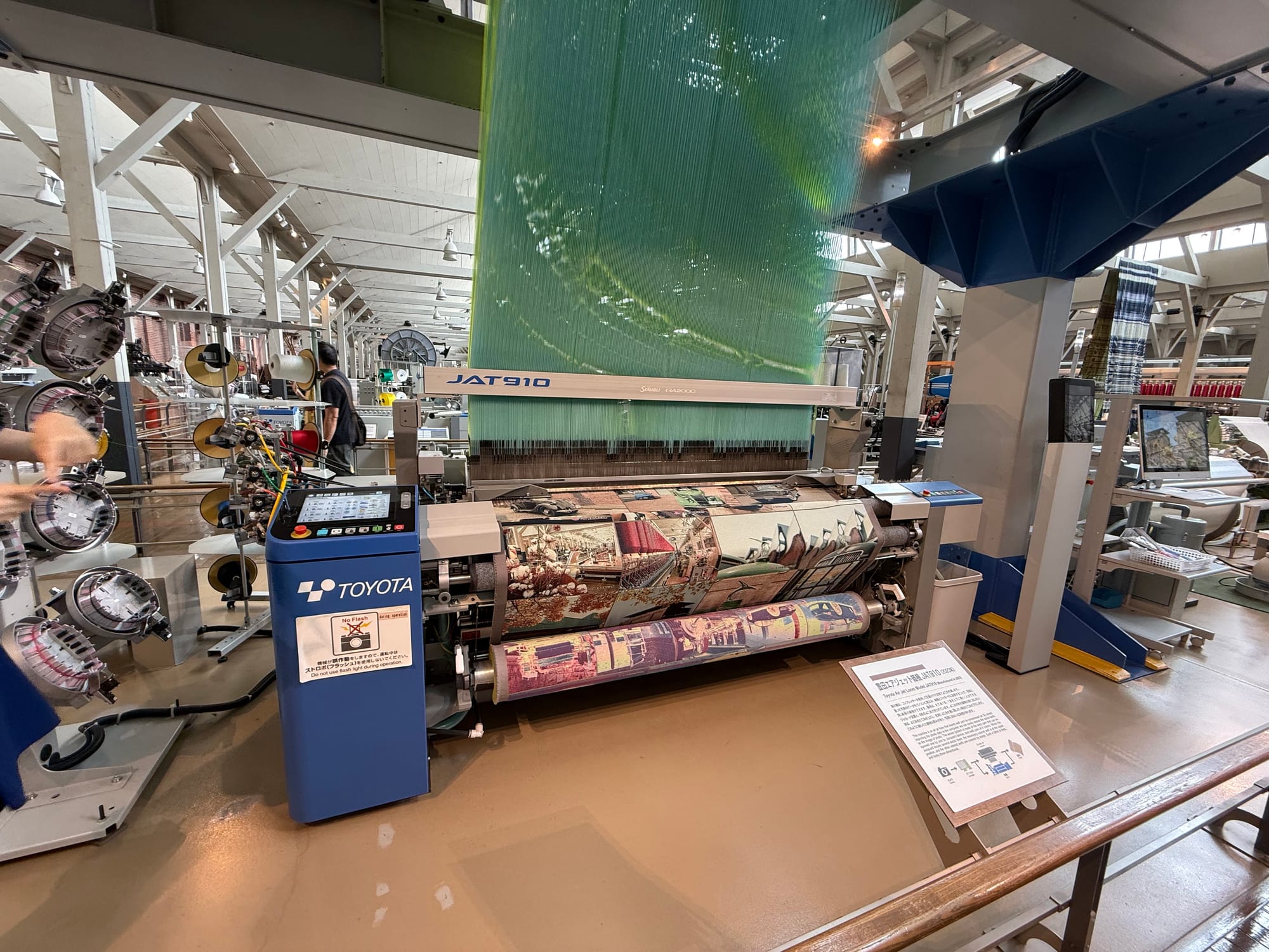Modern Toyota weaving machine operating at the Toyota Commemorative Museum of Industry and Technology, producing patterned fabric while demonstrating advanced textile manufacturing.
